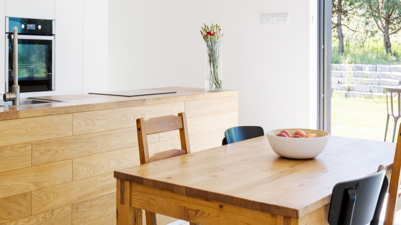 Dining room with an open plan kitchen area with wooden table, chairs, wide table top and patio entry