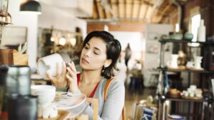 Young woman in a shop, looking at a ceramic jug