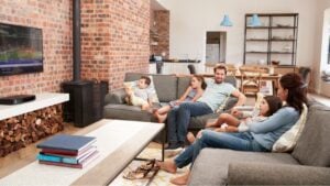 Family Sit On Sofa In Open Plan Lounge Watching Television