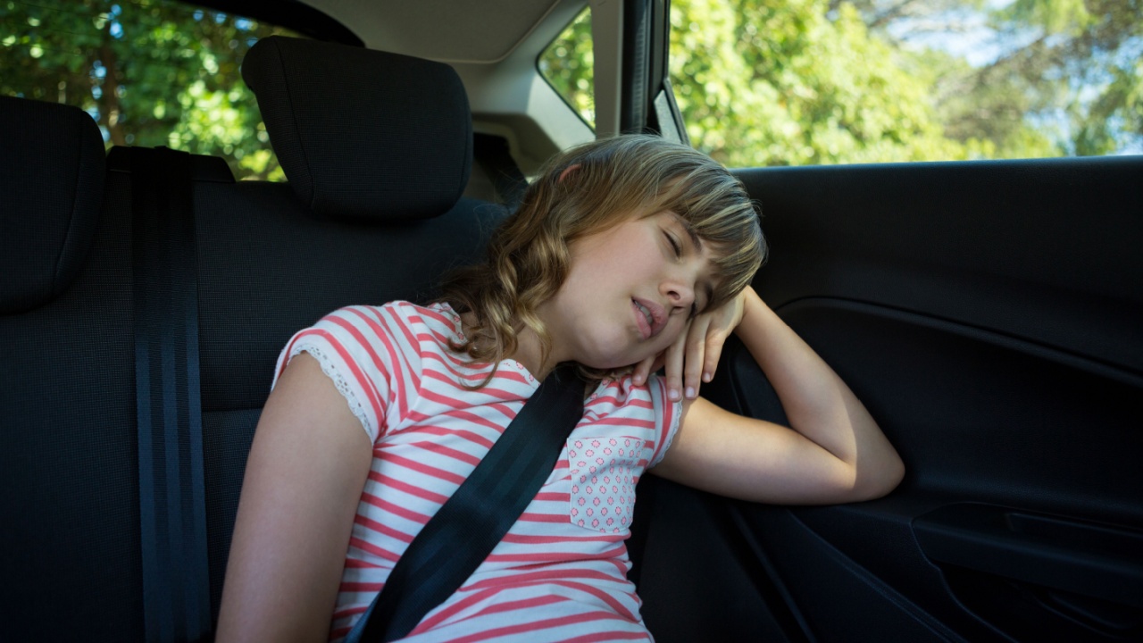 Cute teenage girl sleeping in the back seat of car