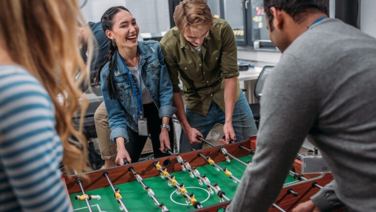 happy multicultural people playing in table soccer at modern office