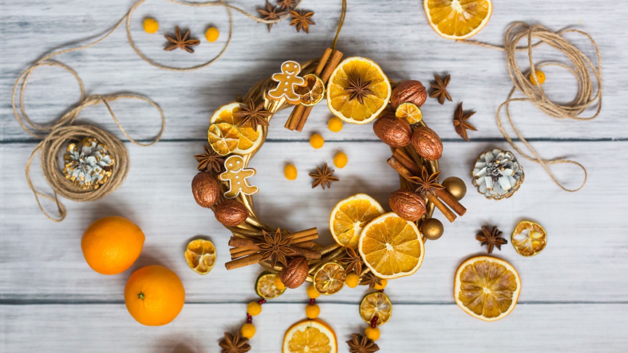Christmas wreath or New Year wreath made of golden branches and walnuts, sticks of cinnamon, flowers of badian or anise, dried oranges and lemons and gingerbread men with full oranges, twine, cones