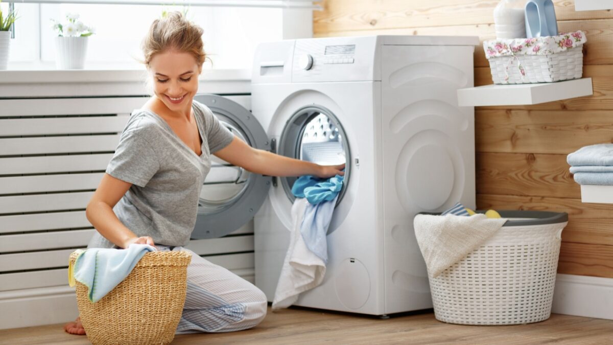 a Happy housewife woman in laundry room with washing machine