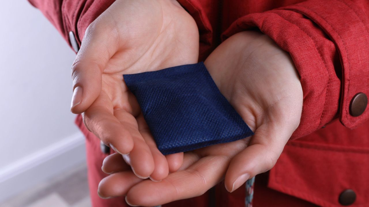 Woman holding hand warmer on white background, closeup