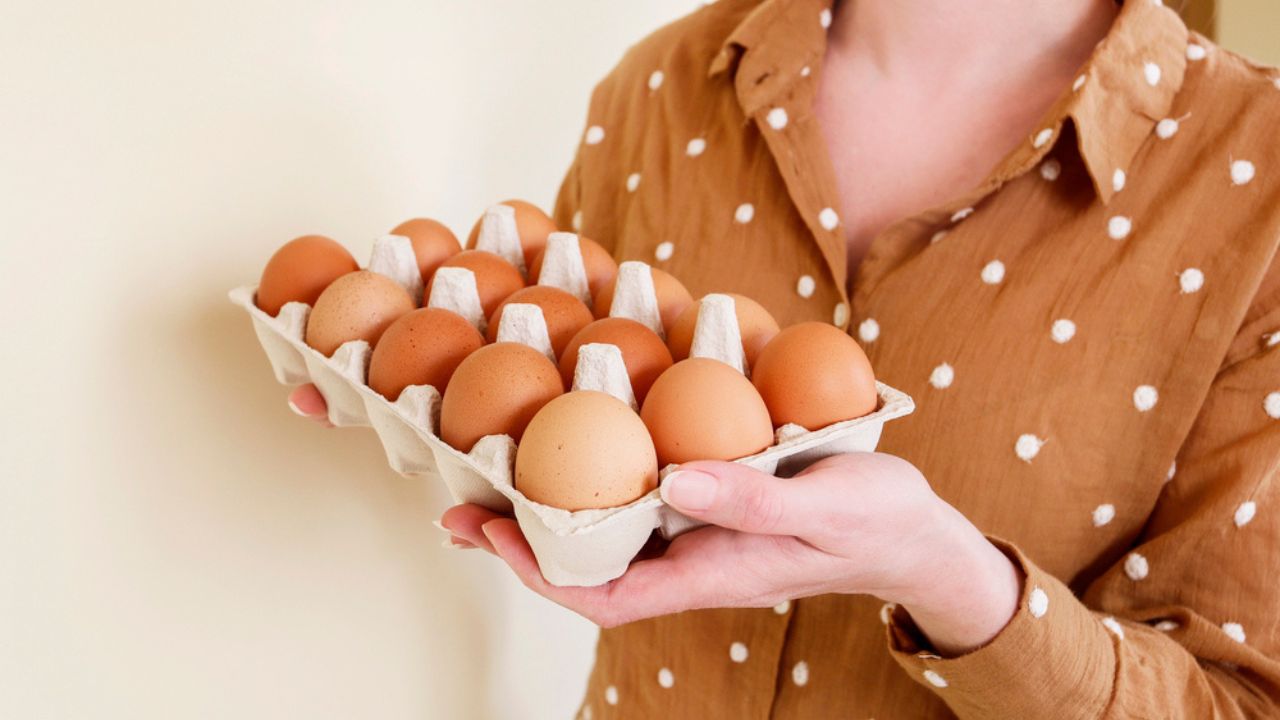 Woman is holding a paper box with eggs.