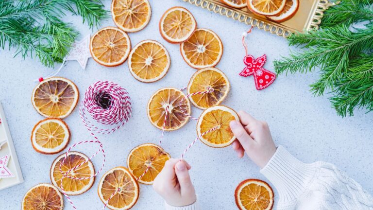 dried orange slices being strung into garland