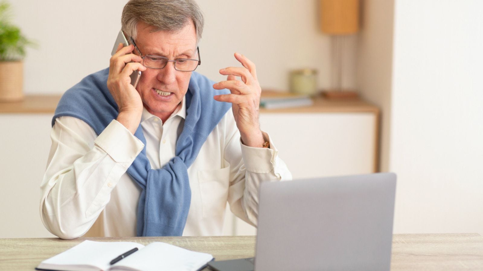 Discontented angry Senior Man Talking On Phone Sitting In his house