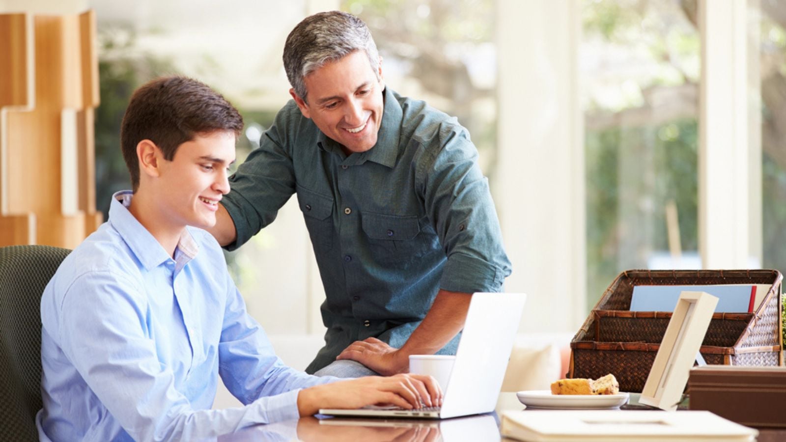 Father And Teenage Son Looking At Laptop