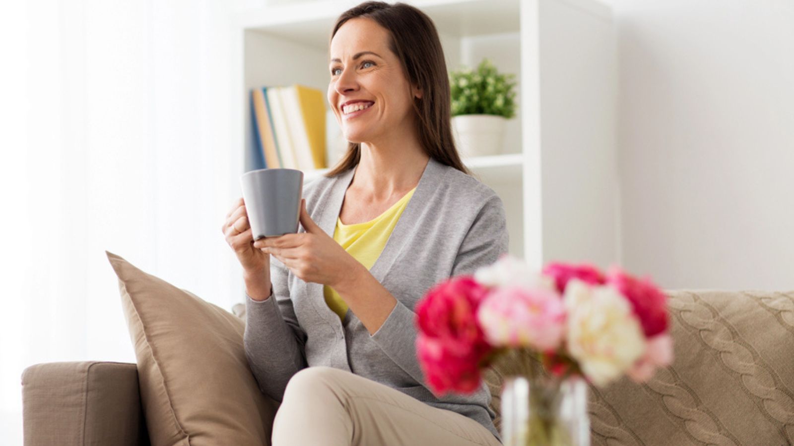 Happy middle aged woman drinking tea or coffee at home