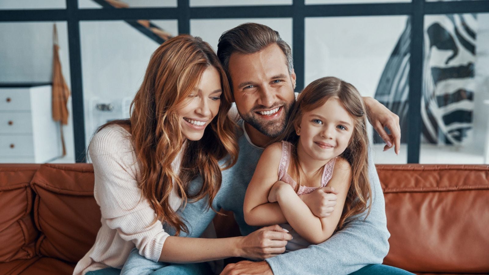 Happy young family smiling and looking at camera while bonding together at home