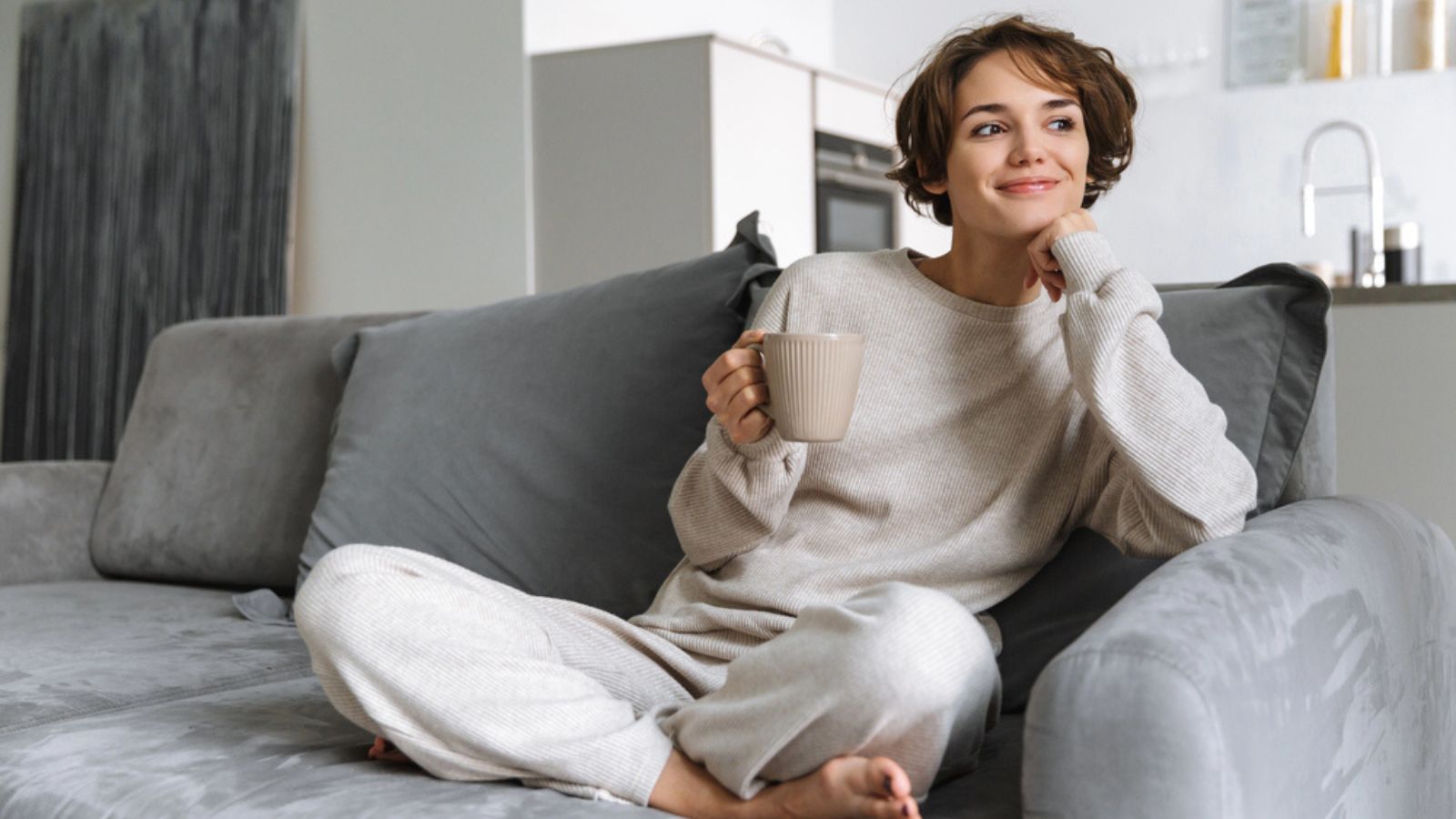 Happy young woman sitting on a couch at home