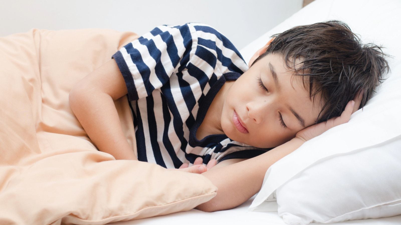 Little boy sleeping on bed
