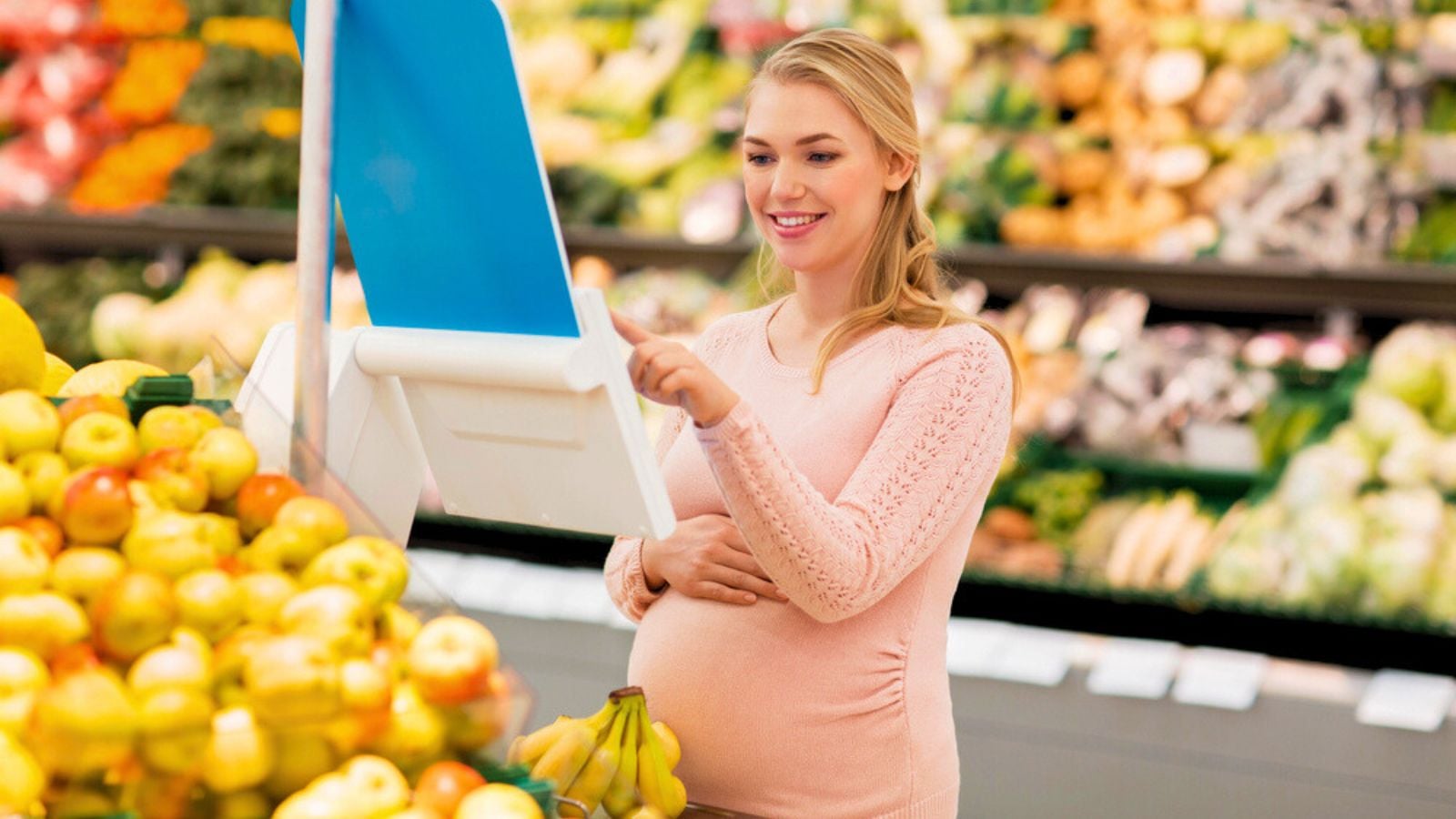 Pregnant woman with bananas on scale at grocery