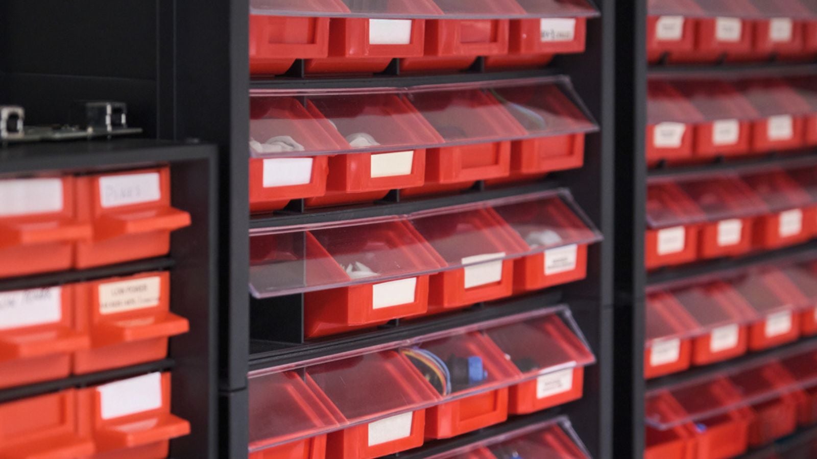 Screws, bolts, nuts, in red storage boxes in a workshop.
