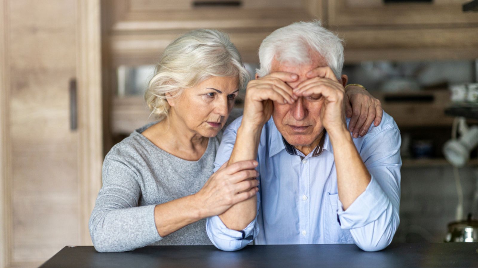 Senior woman comforting her husband at home