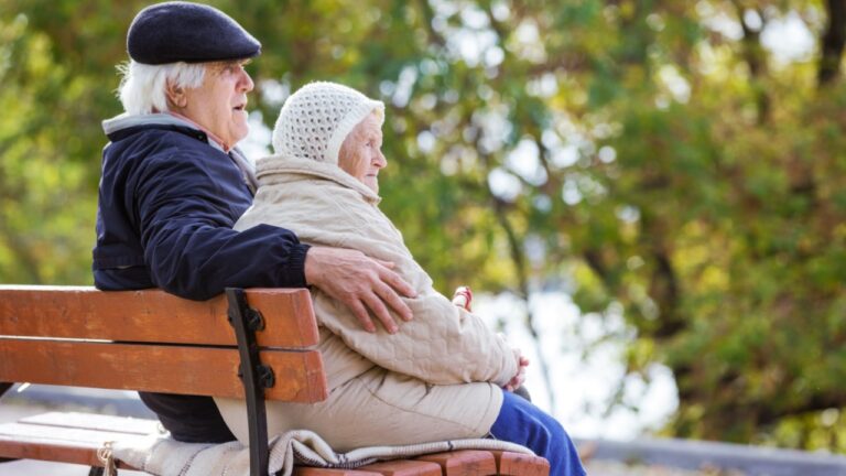 Senior couple sitting on bench in autumn park