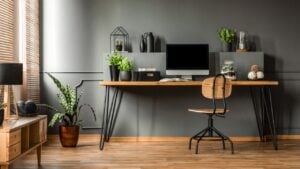 Real photo of a dark interior with wooden desk, chair and computer in the study space in the middle