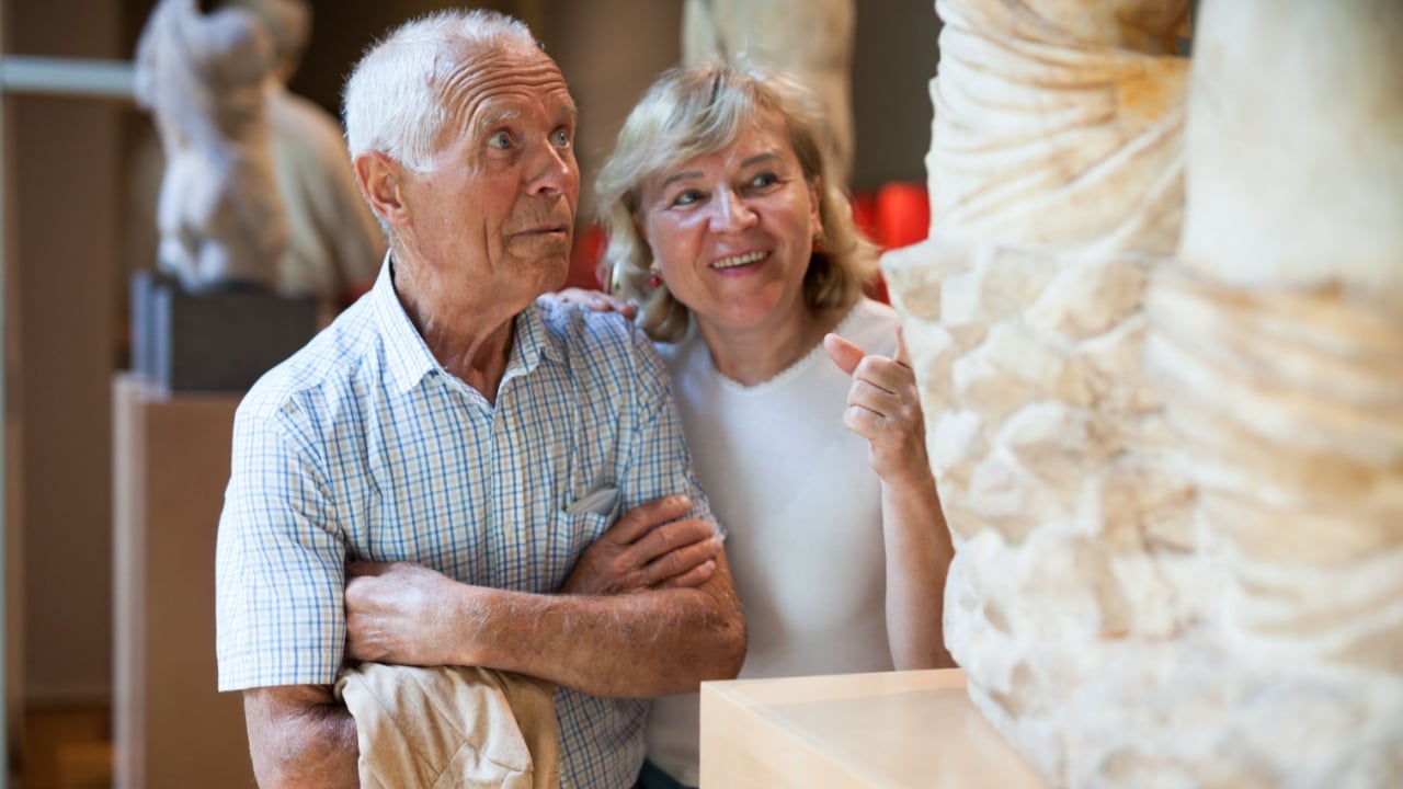 Senior man and woman visiting exposition of museum with exhibits of art