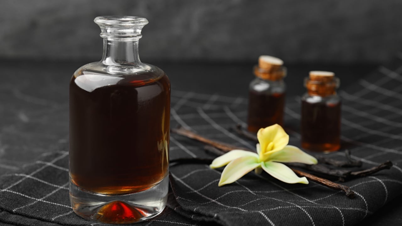 Aromatic homemade vanilla extract on table, closeup. Space for text