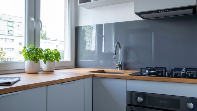 Stylish kitchen counter with stove, sink and herbs in pots
