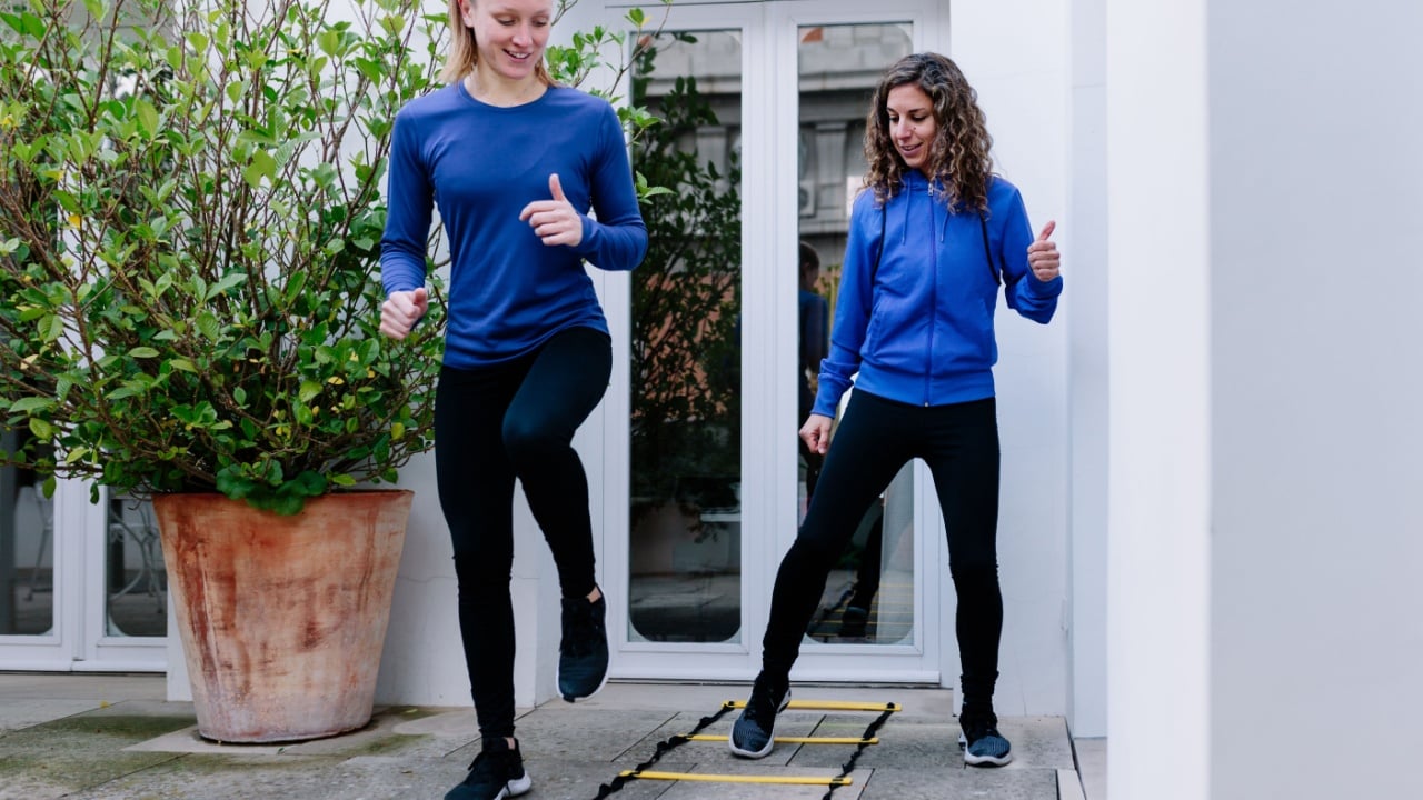 Two young women doing agility ladder exercise on a terrace