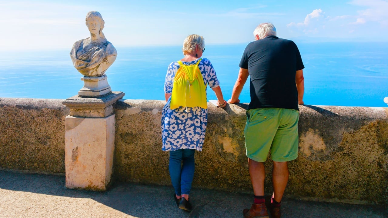 Scenery with couple of senior tourists enjoying views of Ravello village in Italy at Naples. Amalfi coast and landscape with people at Tyrrhenian Sea at Italian Amalfitana coastline in Europe. Summer.