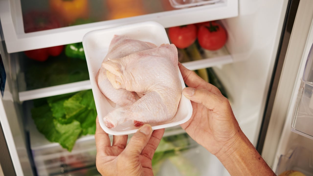 Man taking package of fresh chicken thighs out of refrigerator