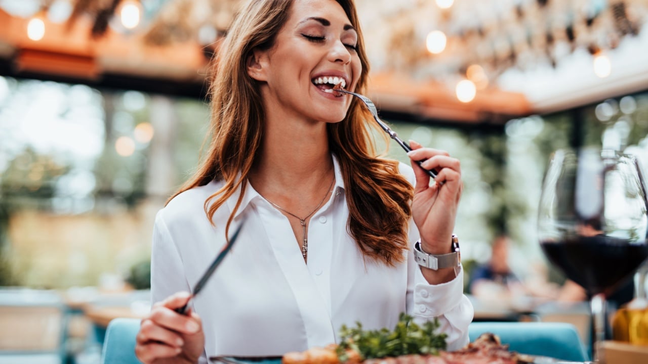 Young beautiful and happy woman enjoying in delicious meal in luxurious restaurant.