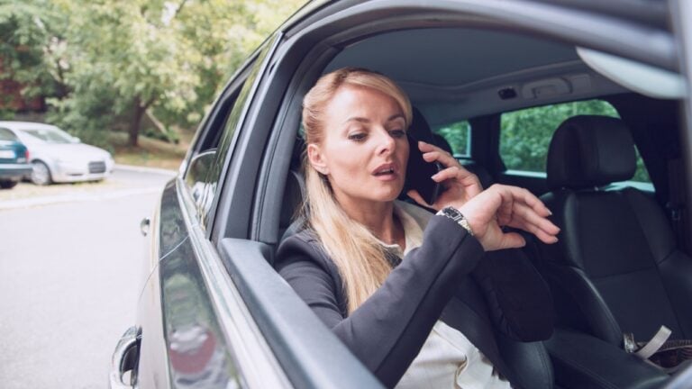 Woman driver looking at her hand watch waiting for the service in the Car. Worried Female upset for the car breakdown sitting inside the vehicle. Businesswoman stuck in traffic