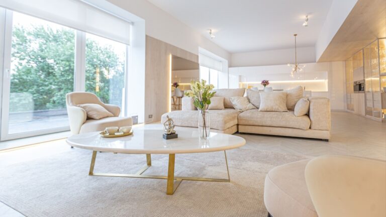 trendy modern interior design of a large studio in white and beige colors with large floor-to-ceiling windows. area of ​​white kitchen with an island and a recreation area