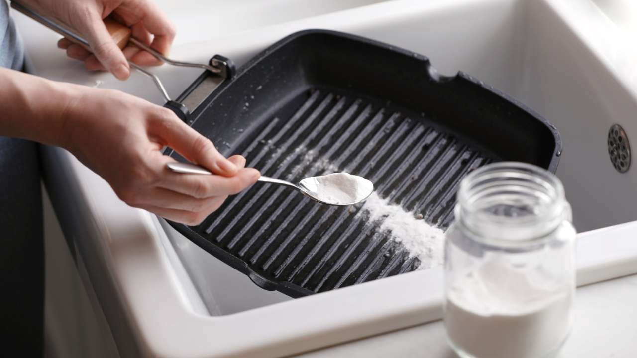 Woman using baking soda to grill pan indoors, closeup