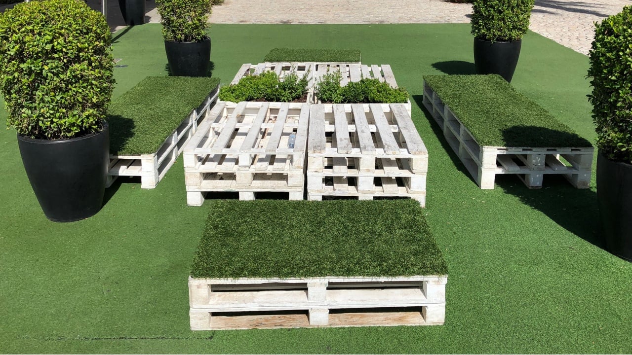 Wooden decor, pallet furniture, green plants and artificial lawn on a street city, urban space