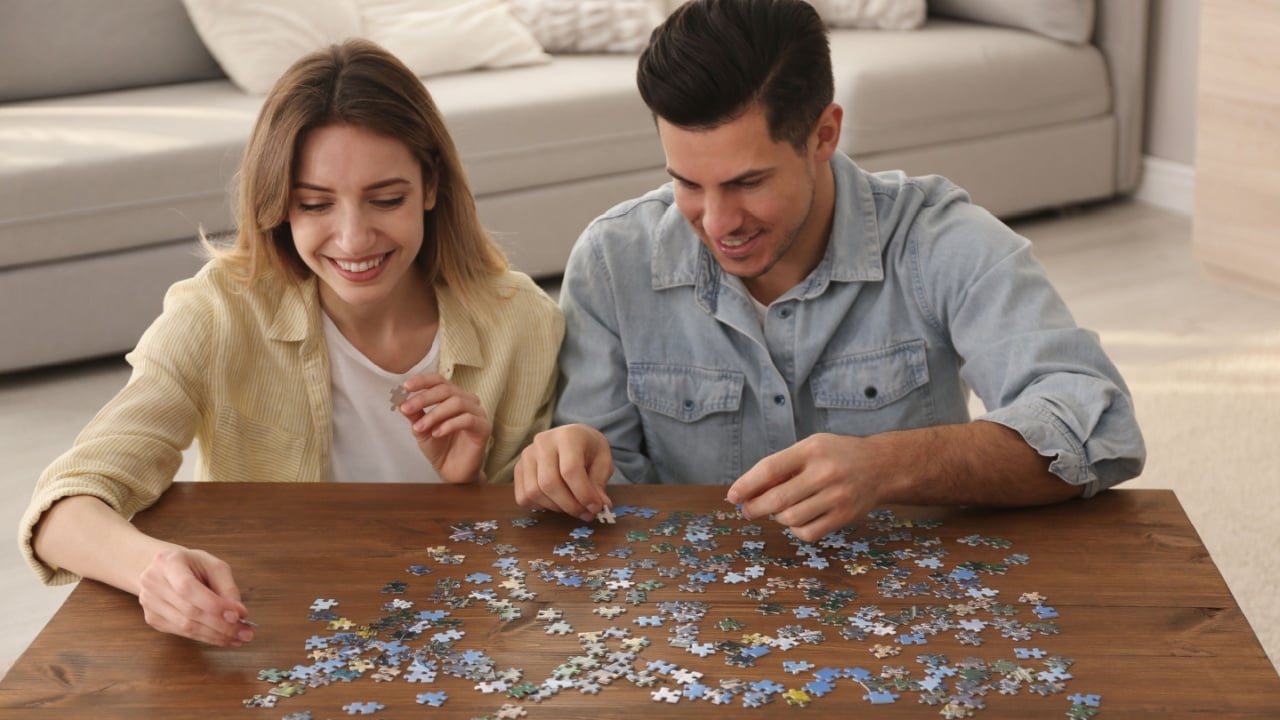 Happy couple playing with puzzles at home