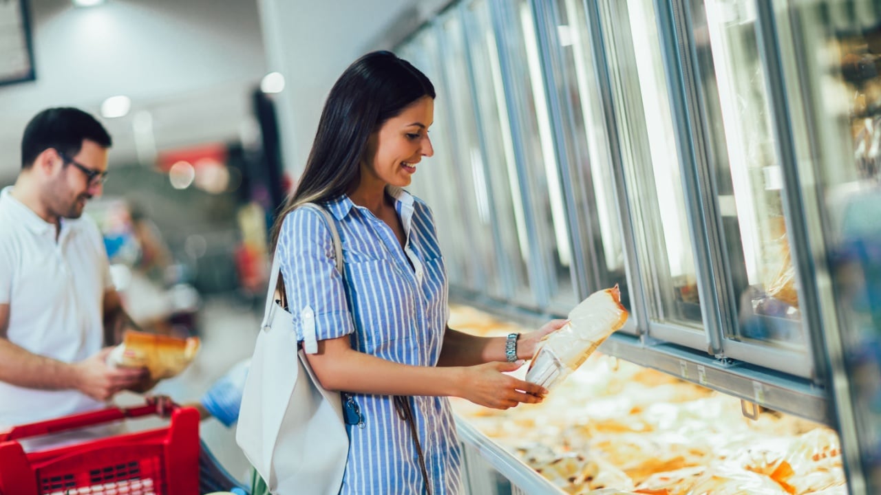 Happy couple buying frozen food in store or supermarket