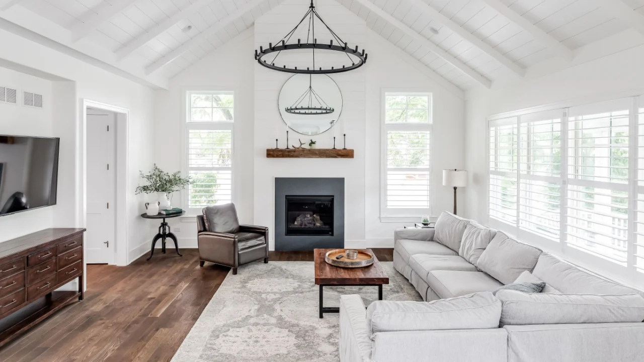 ELMHURST, IL, USA - MAY 26, 2020: A modern farmhouse living room with shiplap, exposed white beams, a fireplace, and furniture on hardwood floors.