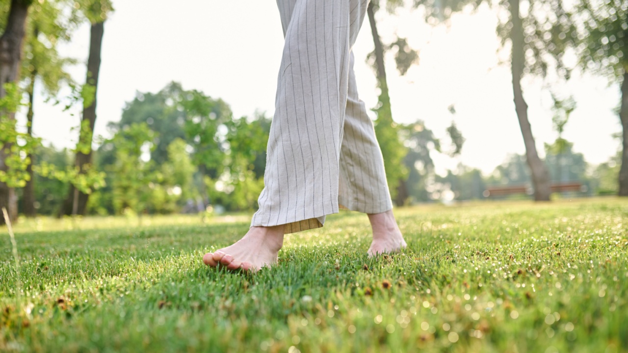 Barefoot woman moving on green lawn