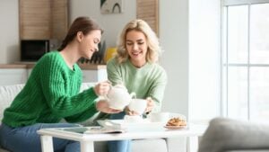 Beautiful young sisters drinking tea at home