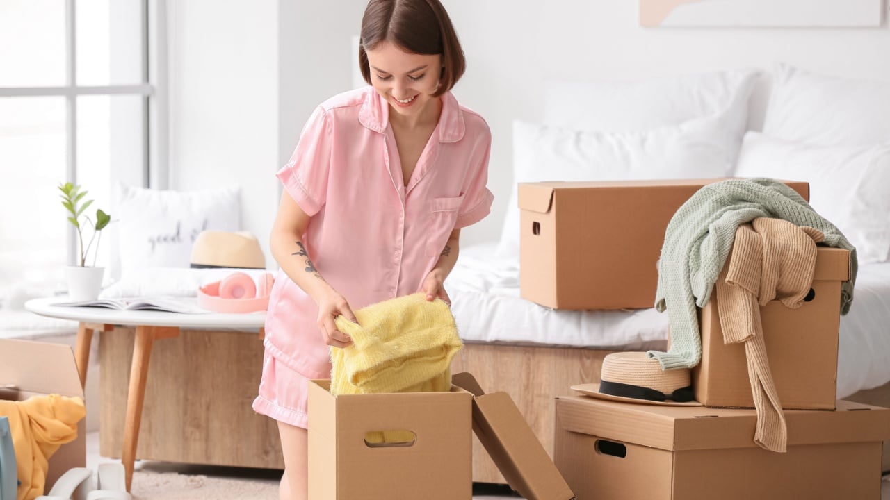 Young woman organizing clothes in bedroom