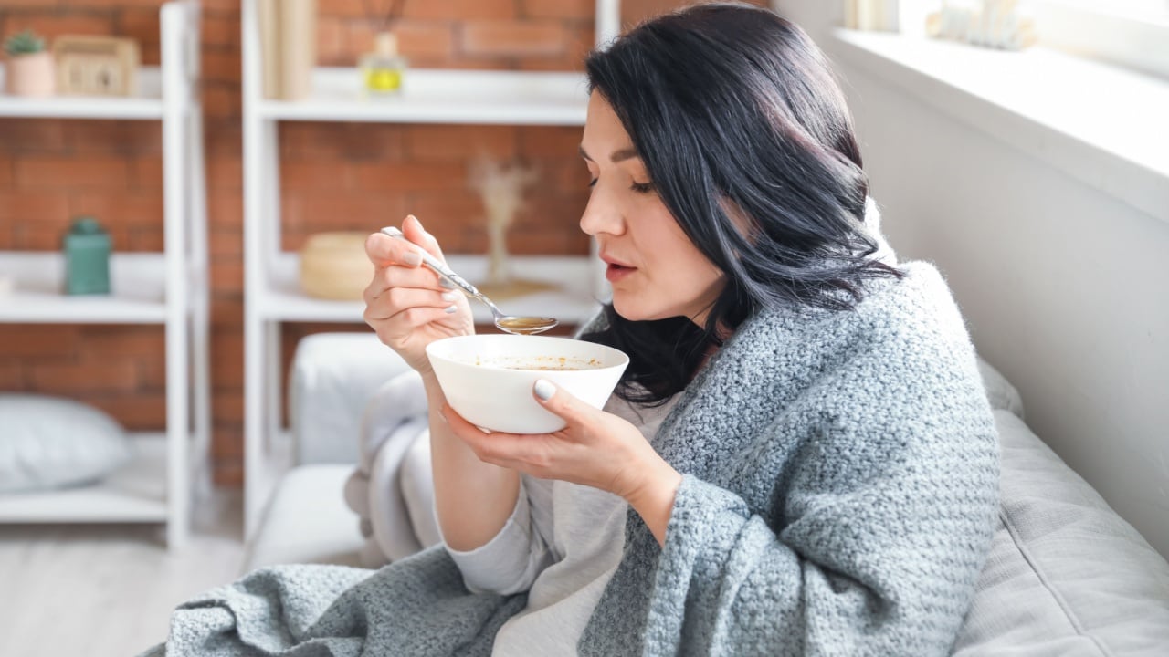 Sick mature woman eating soup at home
