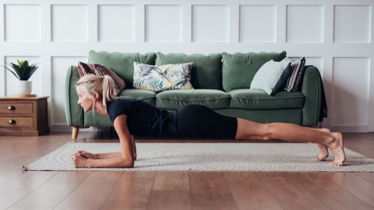 Young woman doing plank exercise at home.