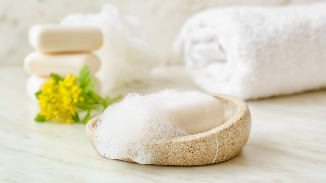 Bowl with soap bar on light background