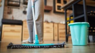 Close up background of unrecognizable woman mopping floors while cleaning cozy apartment, copy space