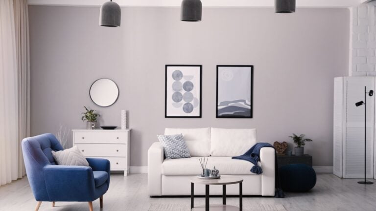 Stylish living room interior with white sofa, armchair and small coffee table