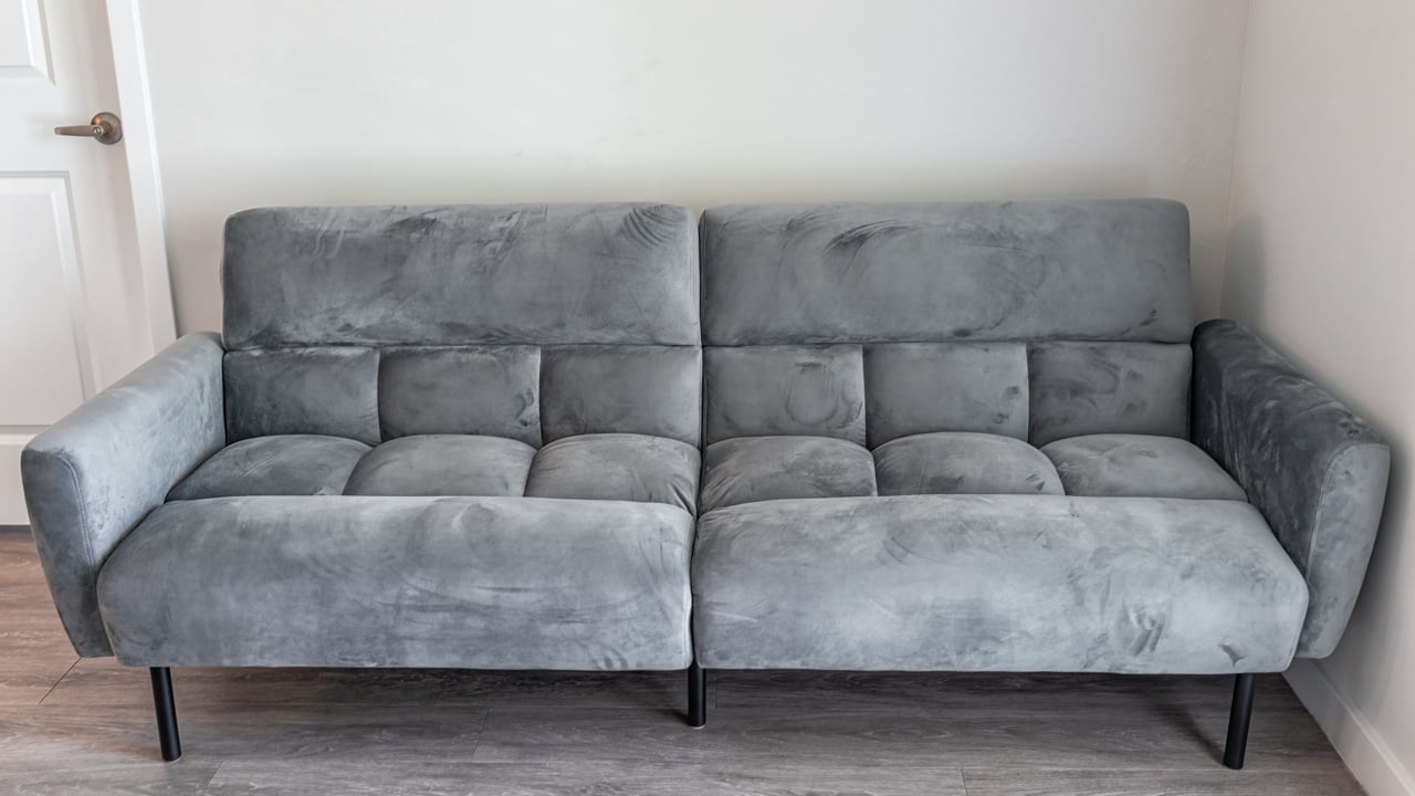 Living room interior with front view of futon couch gray sofa sofabed with microfiber velvet fabric in modern apartment home house