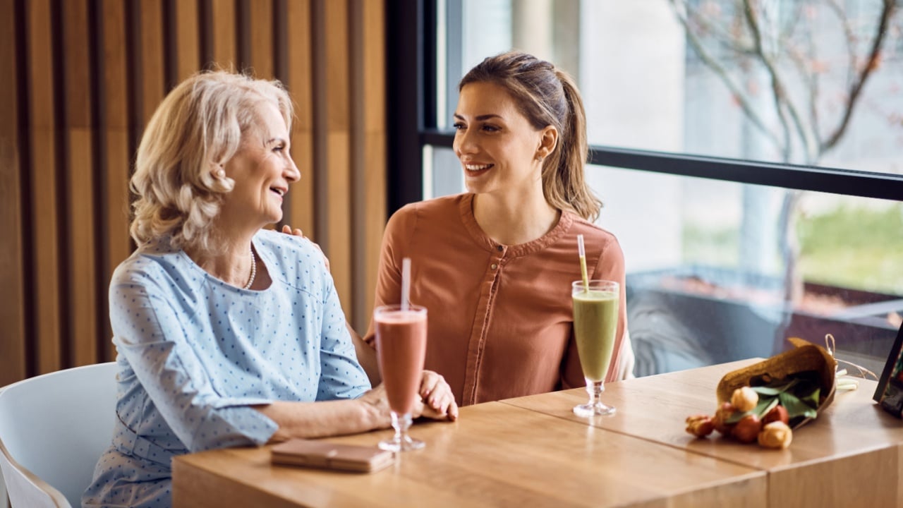 Happy mature mother and her adult daughter enjoying in conversation while spending Mother's day together in a cafe,.