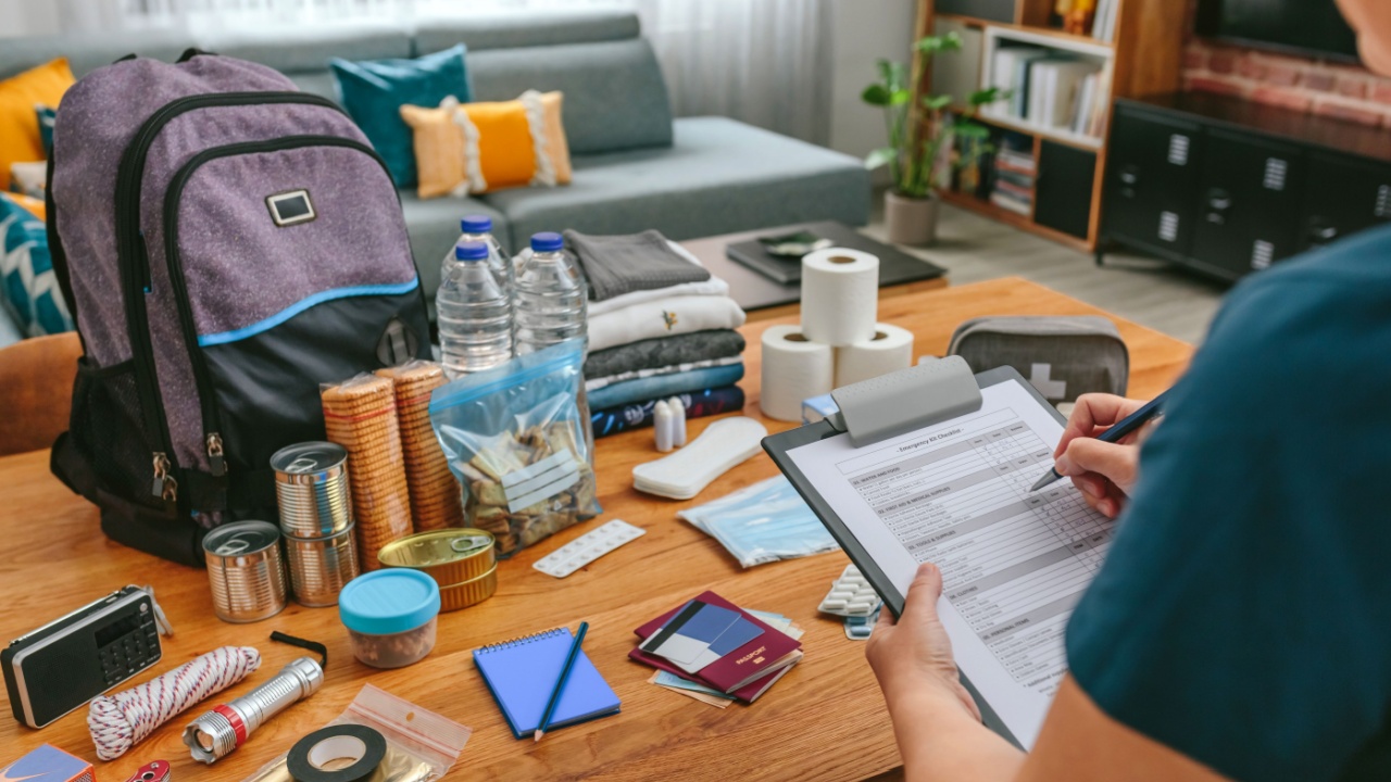 Unrecognizable woman doing checklist of emergency backpack in the living room