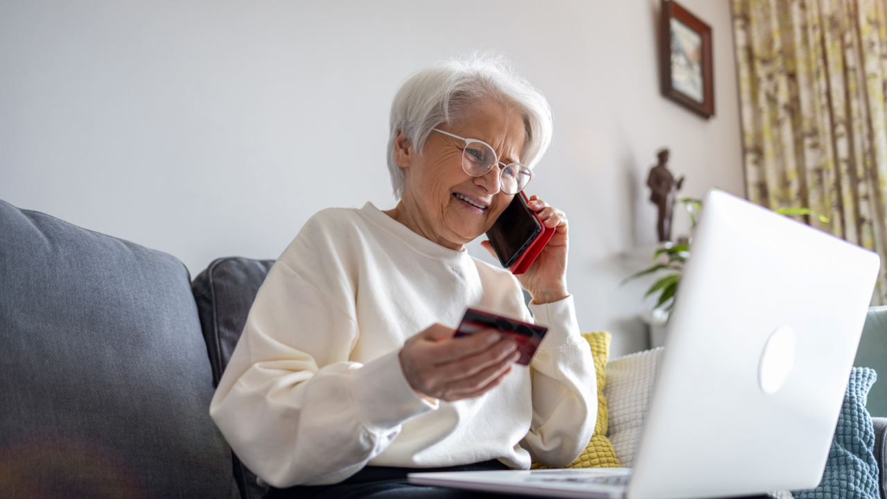 grandma at the computer woman with a phone and credit card living room laptop