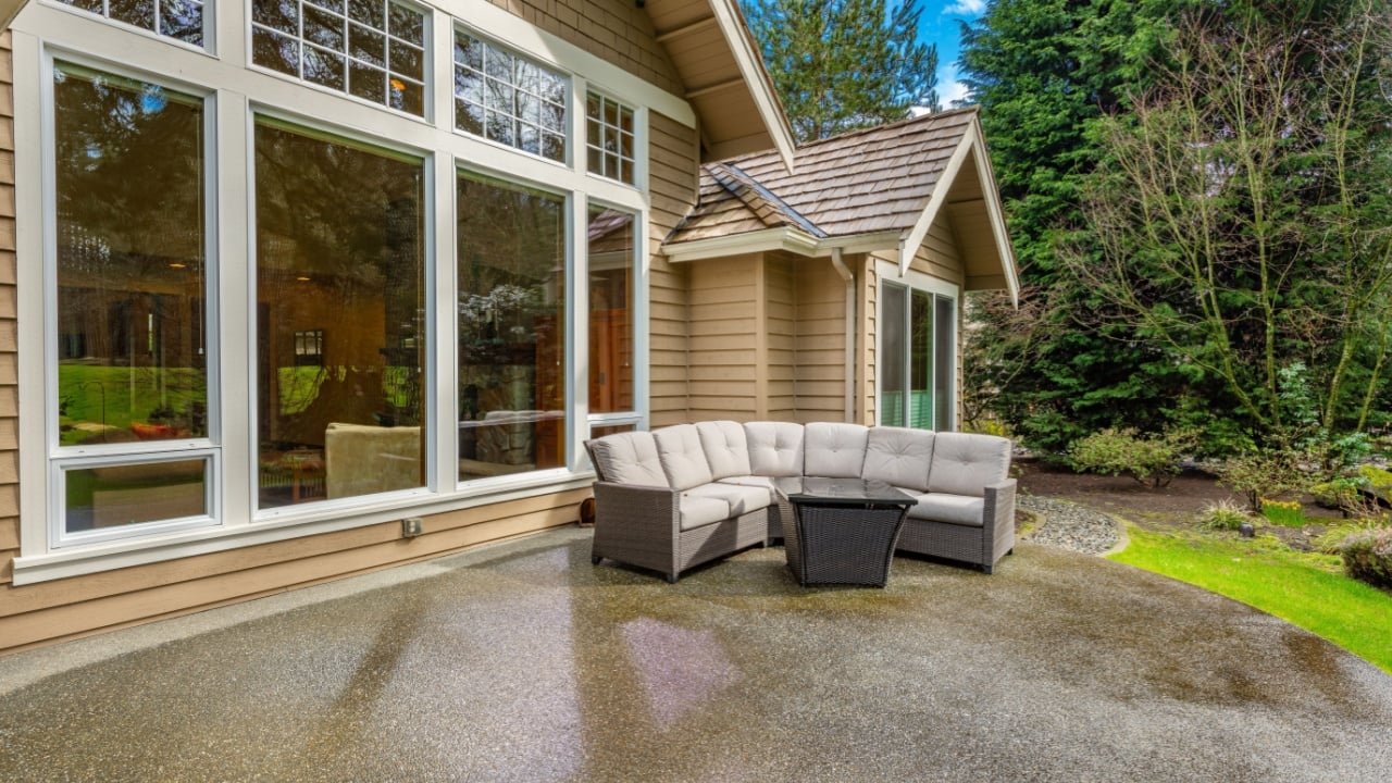 Craftsman house on lushly landscaped lot on a golf course with blue sky and rain on a long driveway