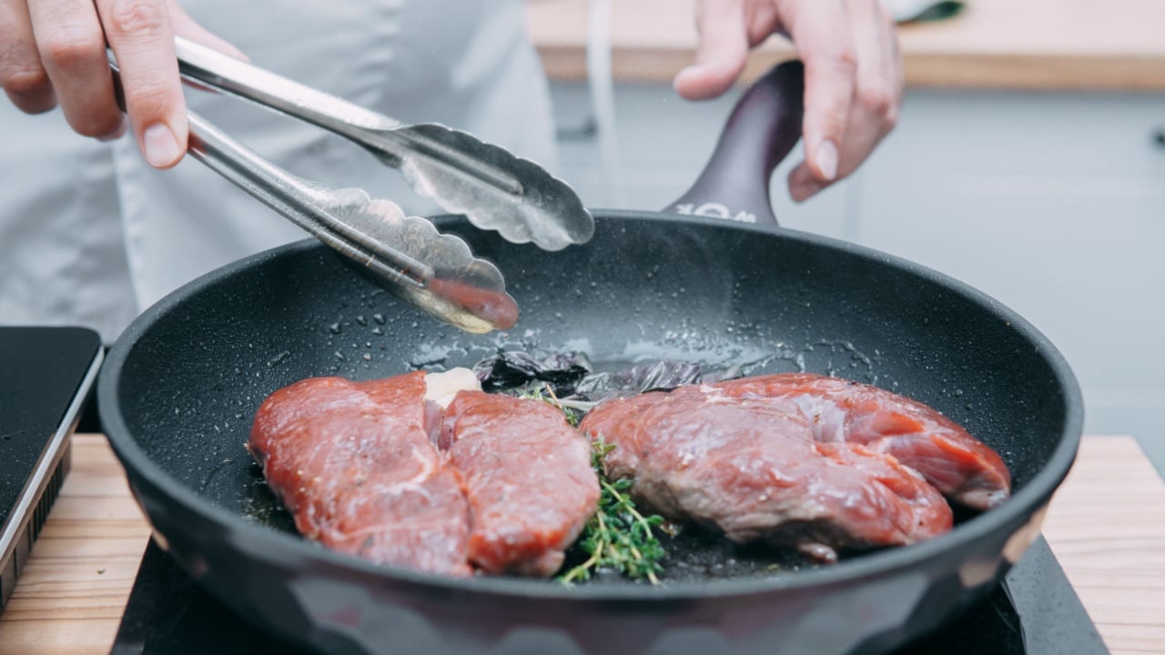 Cooking beef ribeye steak in a frying pan in the cooking class. Steak with spices. Cooking process, close-up.