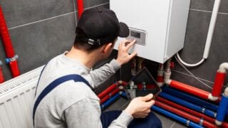 The technician checking the heating system in the boiler room with tablet in hand